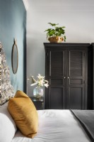 Chambre avec tête de lit rembourrée, mur décoratif bleu canard et placard noir 
