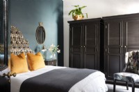 Chambre avec tête de lit rembourrée, mur bleu canard et placards noirs 
