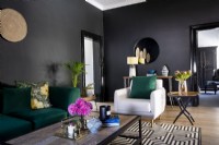 Salon avec murs noirs, tapis géométrique et canapé vert 