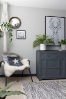 Coin salon avec armoire peinte, cintre pour plantes en macramé et chaise d'appoint 