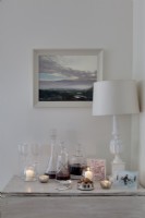 table d'appoint blanche habillée de carafes de vin et lampe de table blanche 