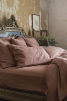 Linge de lit français marron/rouille sur un lit double français ancien et orné 
