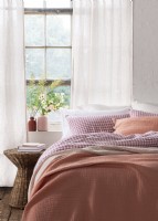 Jeté rose sur un lit double avec du linge de lit à carreaux vichy roses 