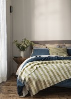 Couverture à carreaux verts sur lit double avec draps bleus 