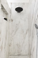 Salle d'eau contemporaine en marbre avec grande pomme de douche. 
