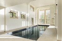 Grande piscine intérieure dans un bâtiment traditionnel avec baie vitrée. 