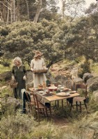 Deux femmes dans un jardin boisé avec coin repas extérieur rustique 