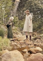 Deux femmes en vêtements vintage marchant sur des rochers dans un ruisseau 