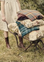 Femme avec une brouette antique remplie de coussins et de couvertures 